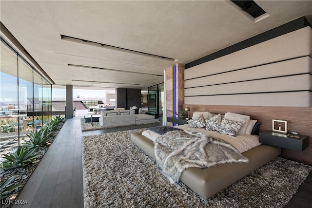 bedroom with expansive windows, hardwood / wood-style floors, and wooden walls