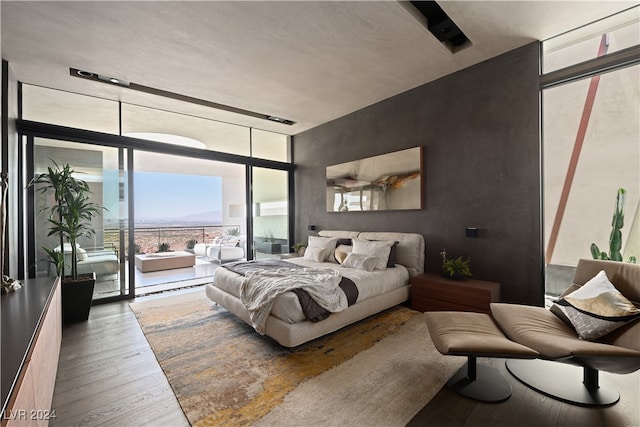 bedroom featuring expansive windows, access to outside, and wood-type flooring