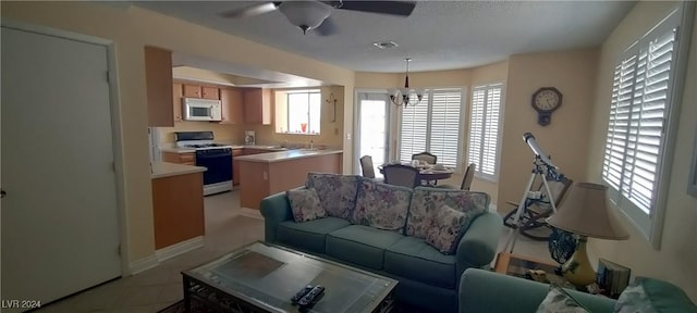 tiled living room with ceiling fan with notable chandelier