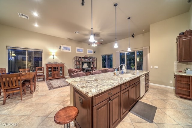 kitchen with ceiling fan, pendant lighting, sink, stainless steel dishwasher, and a kitchen island with sink