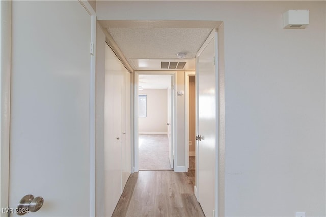 hall featuring a textured ceiling and light hardwood / wood-style flooring