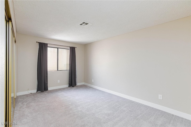 carpeted empty room featuring a textured ceiling