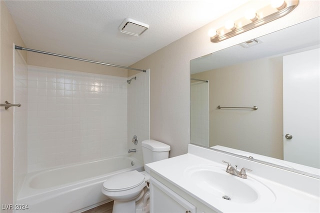 full bathroom with a textured ceiling, tiled shower / bath combo, vanity, and toilet