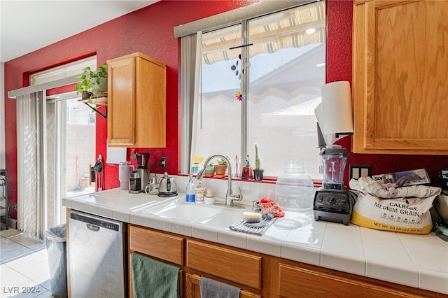 kitchen with dishwasher, light tile patterned floors, tile counters, and sink