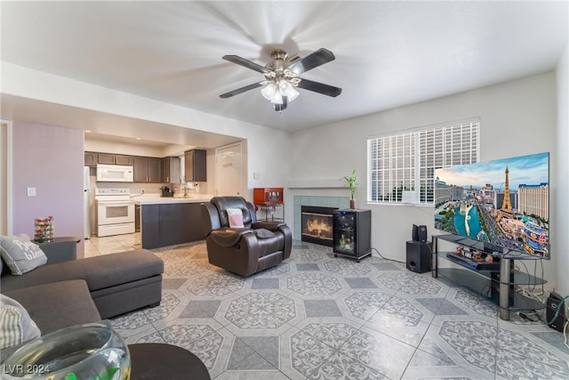 living room with a tiled fireplace and ceiling fan