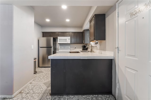 kitchen with dark brown cabinets, light tile patterned flooring, sink, white appliances, and tile countertops