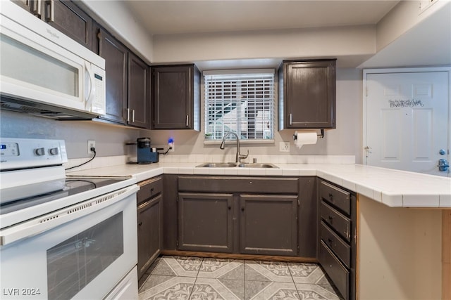 kitchen featuring white appliances, kitchen peninsula, dark brown cabinetry, and sink