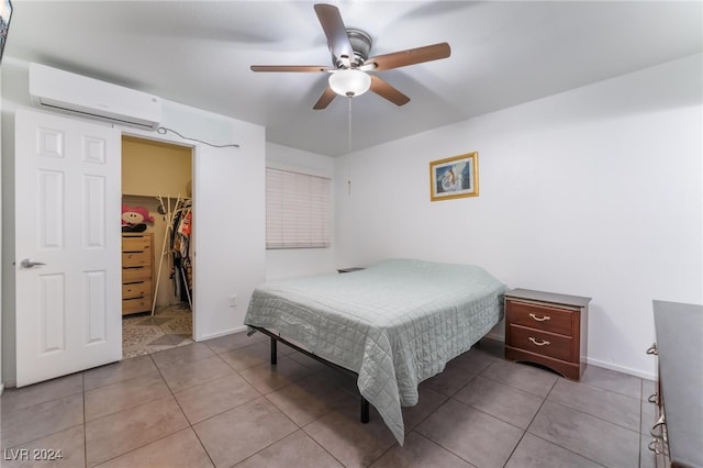 tiled bedroom with ceiling fan, a closet, a wall mounted air conditioner, and a spacious closet