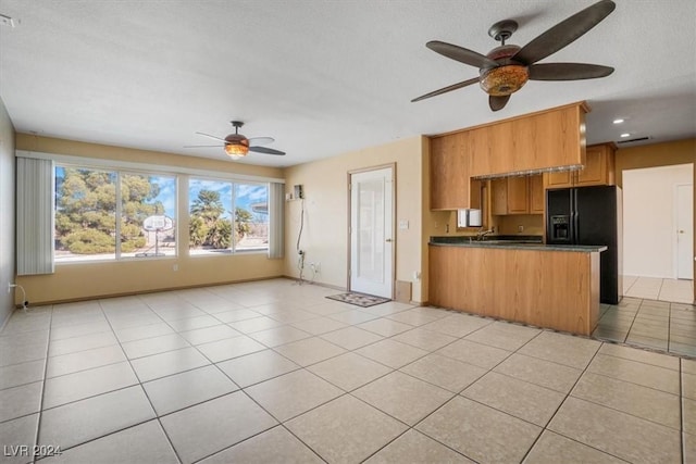 kitchen with light tile patterned floors, ceiling fan, black fridge with ice dispenser, and kitchen peninsula