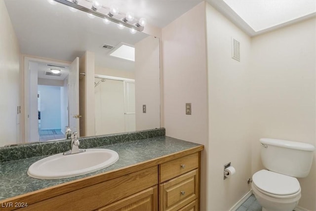 bathroom with toilet, vanity, and a shower with door