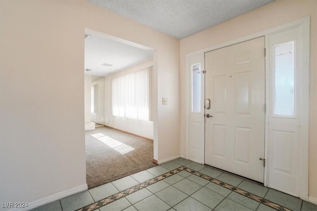 foyer featuring plenty of natural light, light tile patterned floors, and a textured ceiling