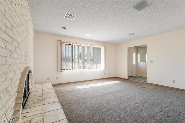 unfurnished living room with a textured ceiling, a brick fireplace, and light colored carpet