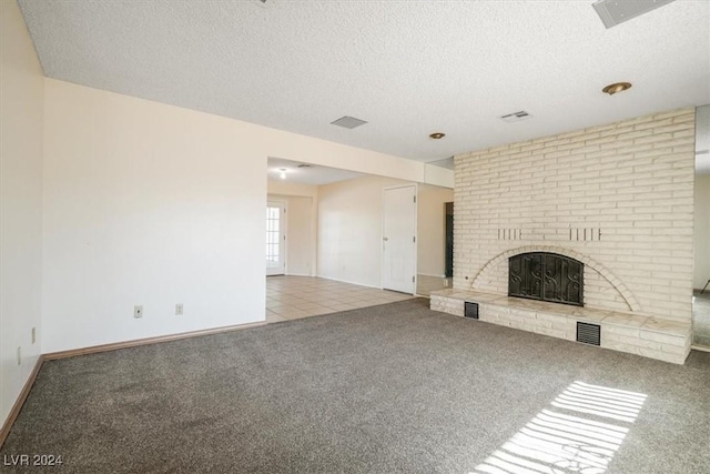 unfurnished living room featuring light carpet, a textured ceiling, and a brick fireplace