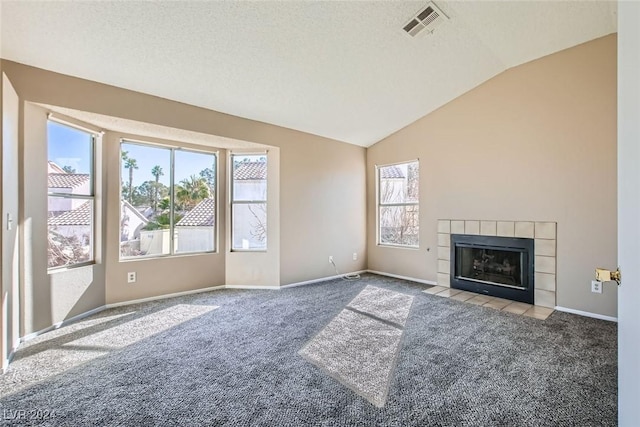 unfurnished living room featuring plenty of natural light, light colored carpet, lofted ceiling, and a tiled fireplace