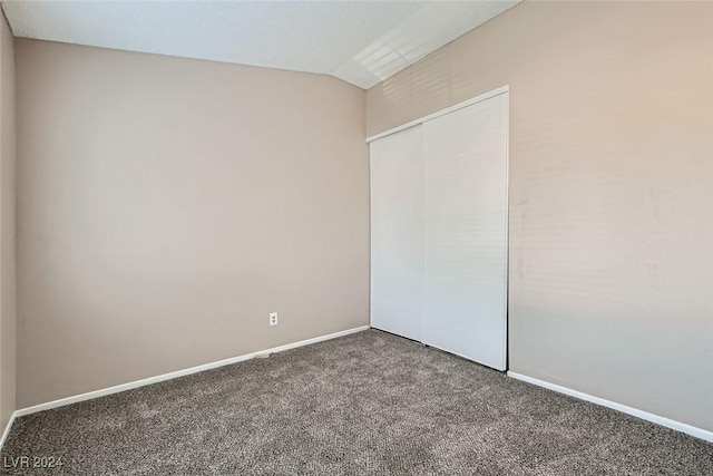 unfurnished bedroom featuring lofted ceiling, a closet, and carpet flooring