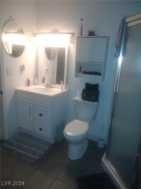 bathroom featuring vanity, a shower with shower door, toilet, and tile patterned flooring