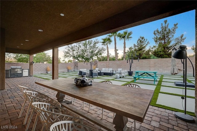 patio terrace at dusk with area for grilling and an outdoor living space