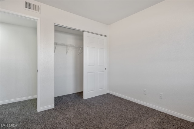 unfurnished bedroom featuring a closet and dark colored carpet