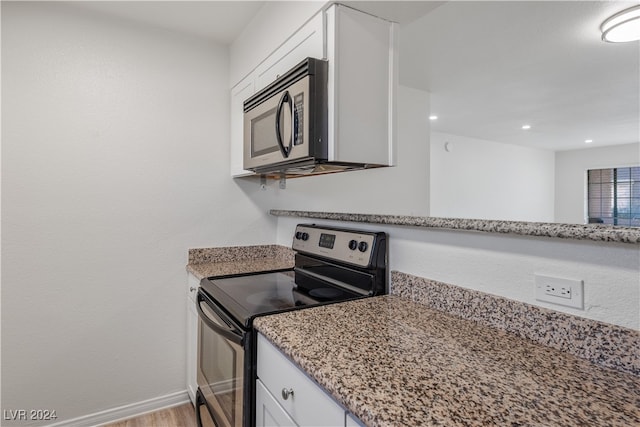 kitchen with light stone countertops, light wood-type flooring, white cabinetry, and appliances with stainless steel finishes