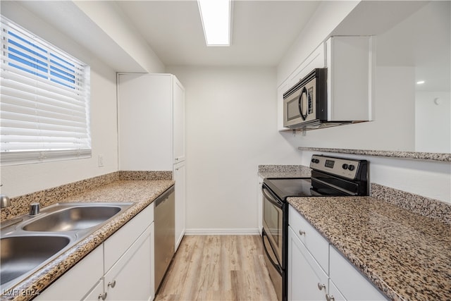 kitchen with light stone counters, white cabinets, sink, appliances with stainless steel finishes, and light hardwood / wood-style floors