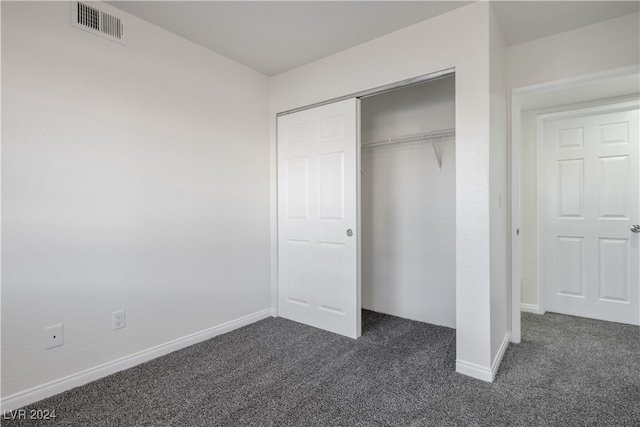 unfurnished bedroom featuring dark carpet and a closet