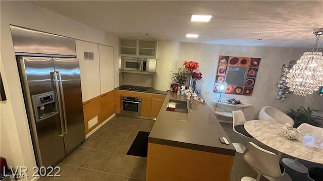 kitchen featuring dark tile patterned floors, sink, white cabinetry, an inviting chandelier, and appliances with stainless steel finishes