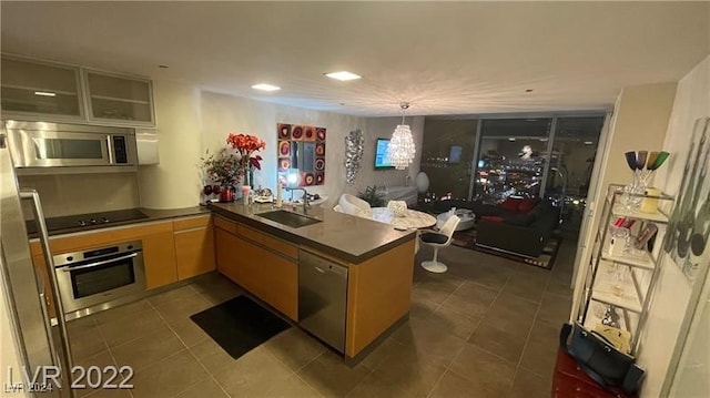 kitchen with appliances with stainless steel finishes, kitchen peninsula, sink, and dark tile patterned floors