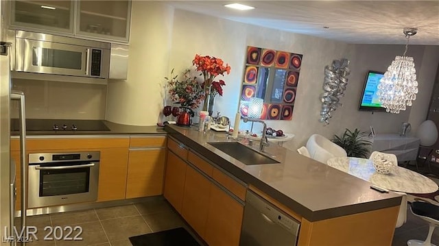 kitchen featuring dark tile patterned flooring, sink, kitchen peninsula, stainless steel appliances, and a notable chandelier