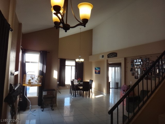 dining area with light tile patterned floors, high vaulted ceiling, and a notable chandelier