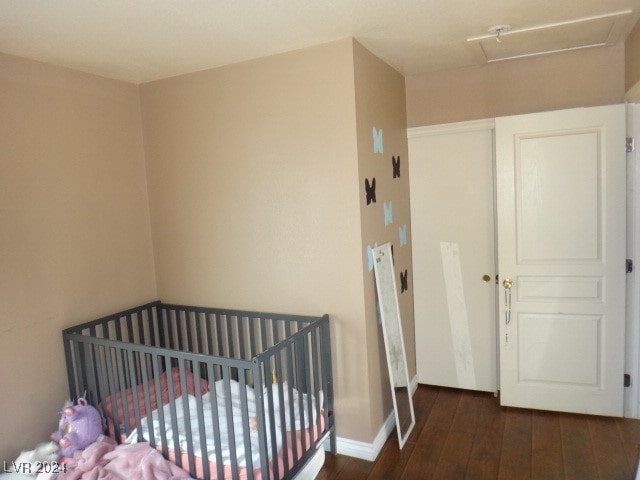 bedroom with a crib and dark hardwood / wood-style floors