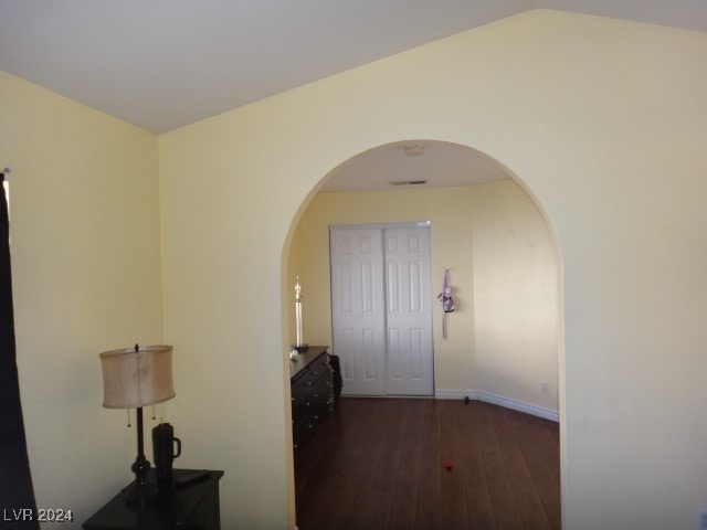 hallway with vaulted ceiling and dark hardwood / wood-style floors