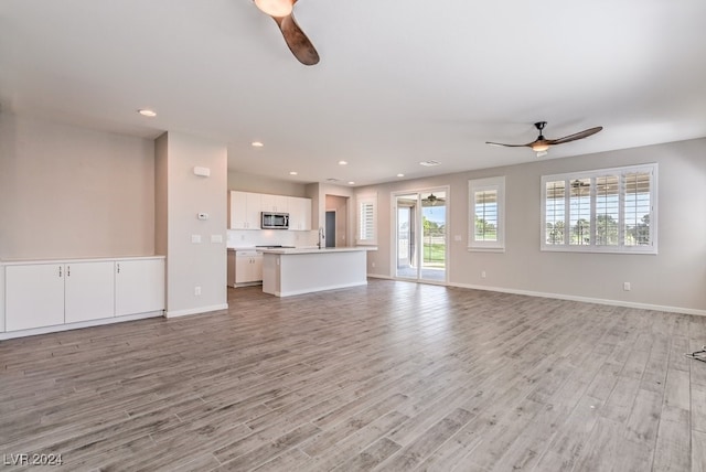 unfurnished living room featuring light wood-type flooring, sink, and ceiling fan