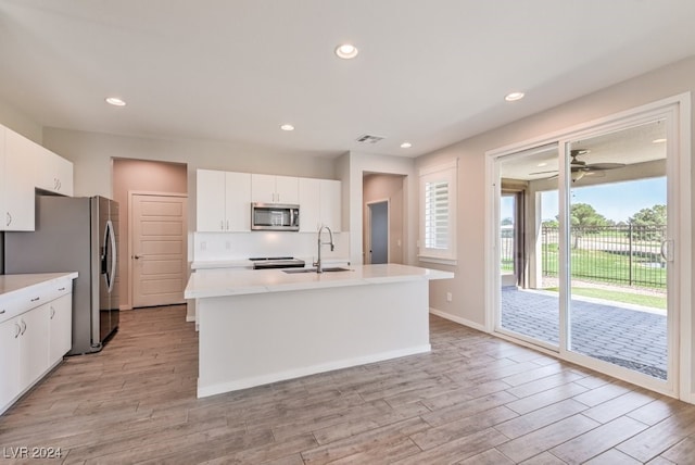 kitchen with light hardwood / wood-style flooring, stainless steel appliances, white cabinets, and sink