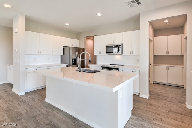 kitchen with sink, a center island with sink, white cabinetry, appliances with stainless steel finishes, and light wood-type flooring