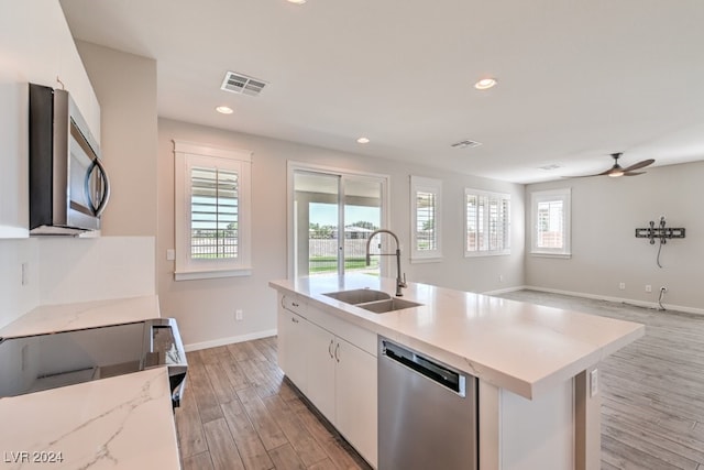 kitchen with appliances with stainless steel finishes, a healthy amount of sunlight, a center island with sink, and white cabinetry