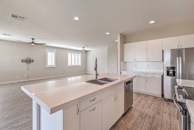 kitchen with sink, a kitchen island with sink, light hardwood / wood-style flooring, white cabinetry, and stainless steel appliances