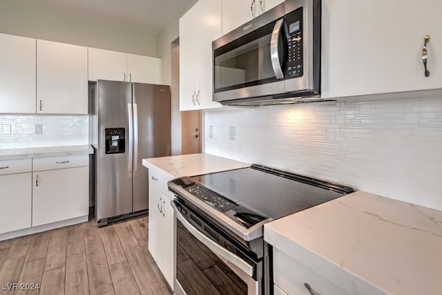 kitchen featuring backsplash, stainless steel appliances, light wood-type flooring, and white cabinets