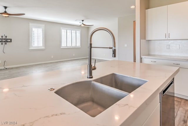 kitchen featuring light stone counters, white cabinets, sink, tasteful backsplash, and light hardwood / wood-style floors