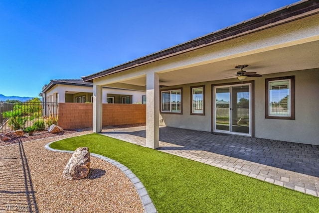 rear view of house featuring ceiling fan and a patio area