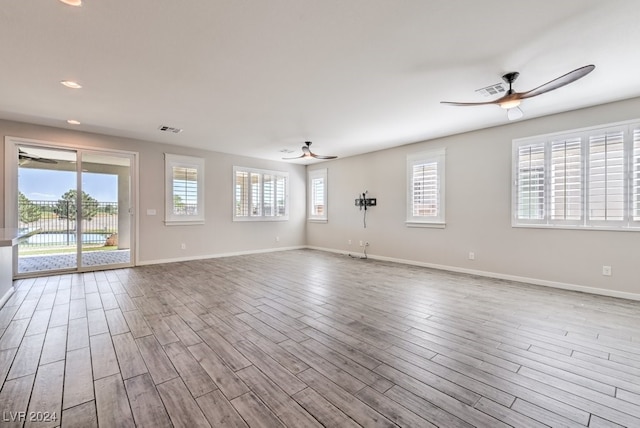 spare room with light wood-type flooring, ceiling fan, and a wealth of natural light