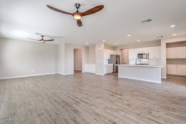 unfurnished living room with light hardwood / wood-style flooring, ceiling fan, and sink