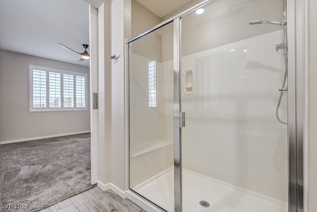 bathroom featuring ceiling fan, wood-type flooring, and an enclosed shower