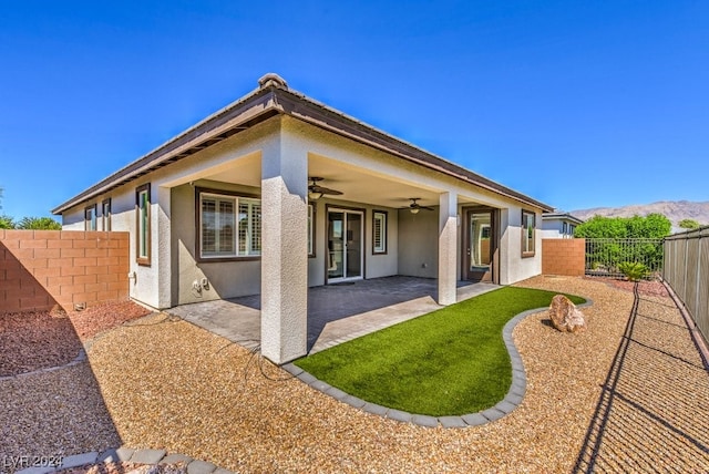 rear view of house with a mountain view, ceiling fan, and a patio area