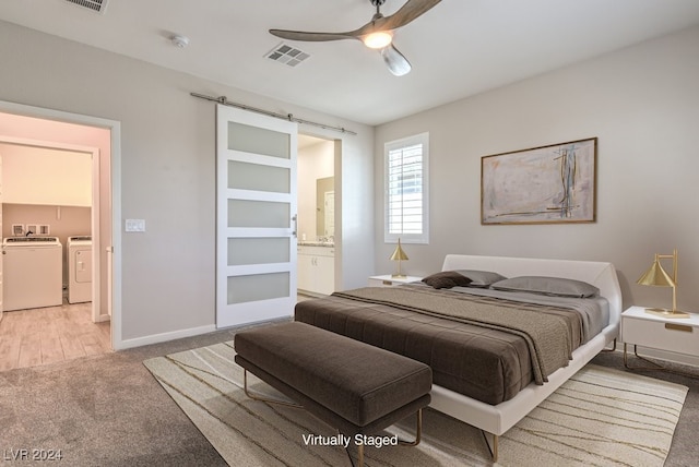 carpeted bedroom featuring a barn door, ceiling fan, washer and dryer, and ensuite bathroom