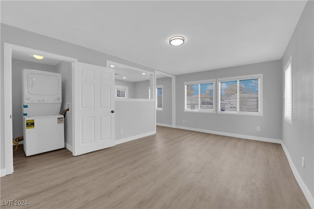 unfurnished living room with light hardwood / wood-style floors and stacked washer / drying machine