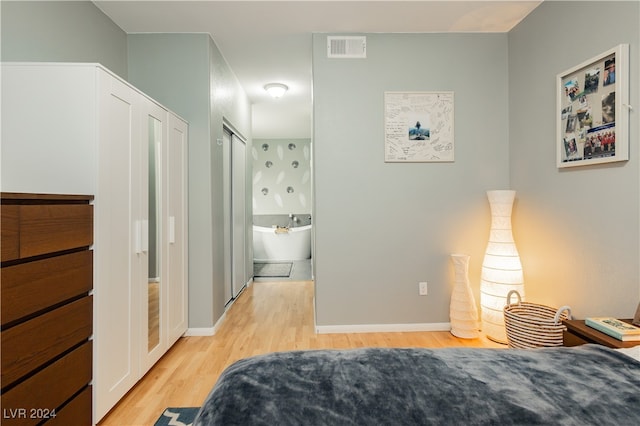 bedroom with connected bathroom and light hardwood / wood-style flooring