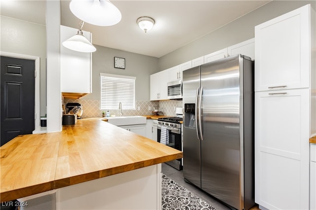 kitchen with hanging light fixtures, tasteful backsplash, white cabinets, kitchen peninsula, and stainless steel appliances