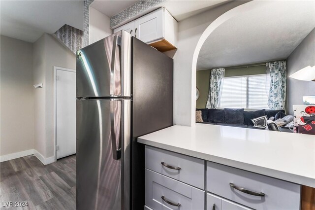 kitchen with stainless steel fridge, white cabinetry, and dark hardwood / wood-style flooring