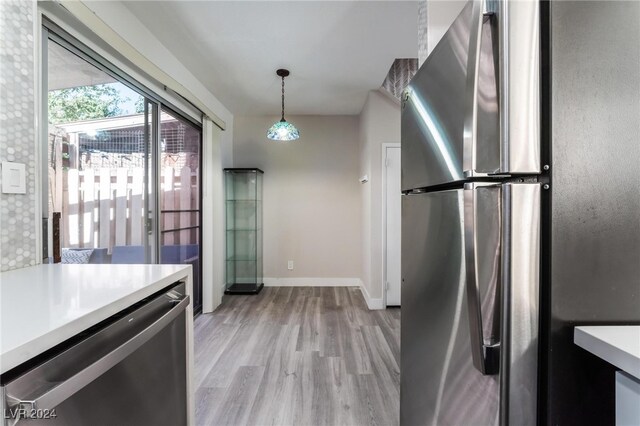 kitchen with light hardwood / wood-style flooring, decorative light fixtures, and stainless steel fridge