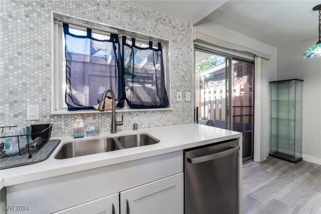 kitchen with pendant lighting, dishwasher, sink, white cabinetry, and light hardwood / wood-style flooring